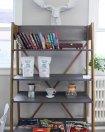 A shelf with a few products as well as books and magazines to read.